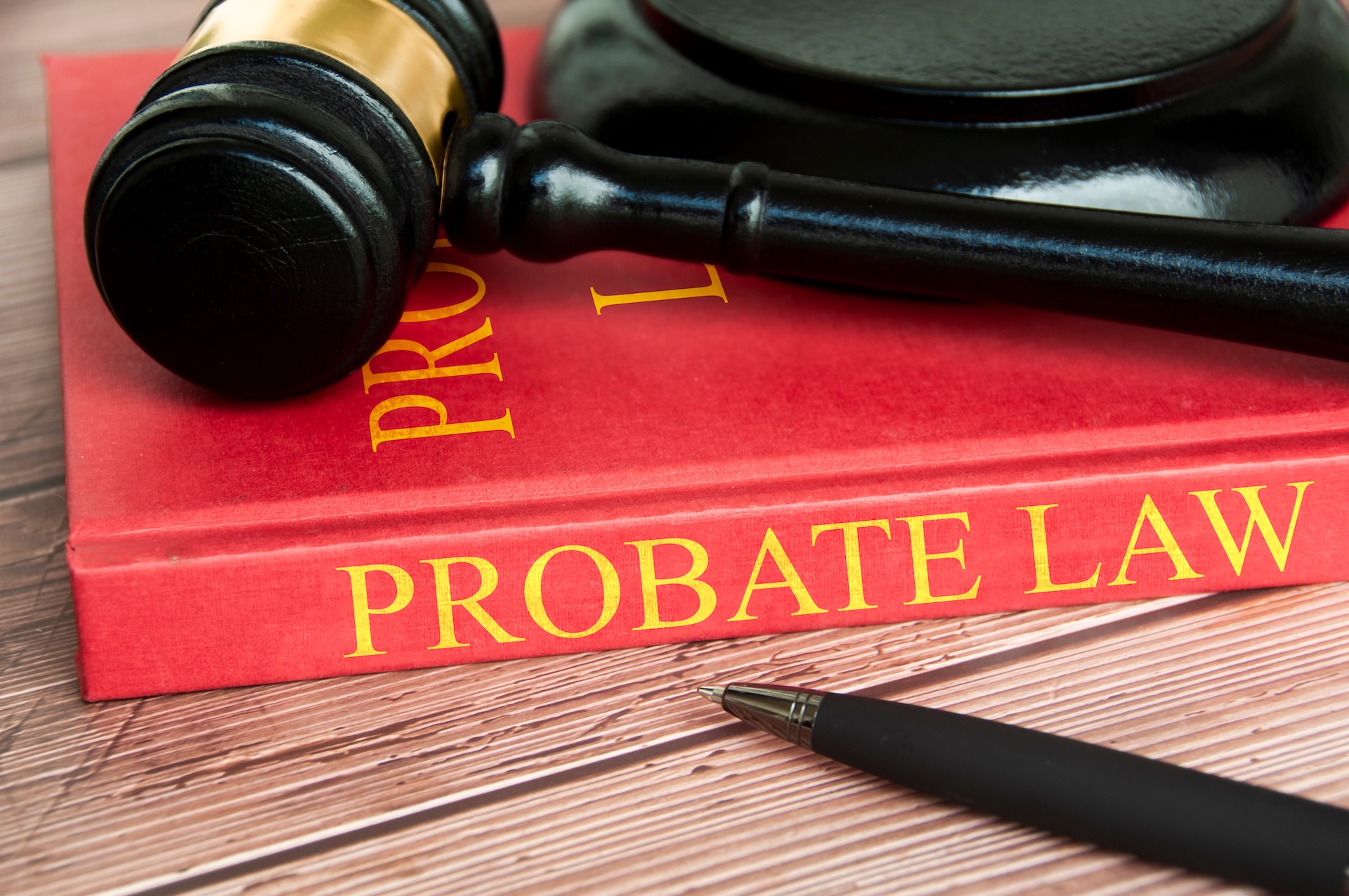 A judge’s gavel rests on a red book titled "Probate Law" in gold letters, with a black pen lying nearby—symbolizing the authority and guidance found in a Houston Estate Planning and Probate Guide.