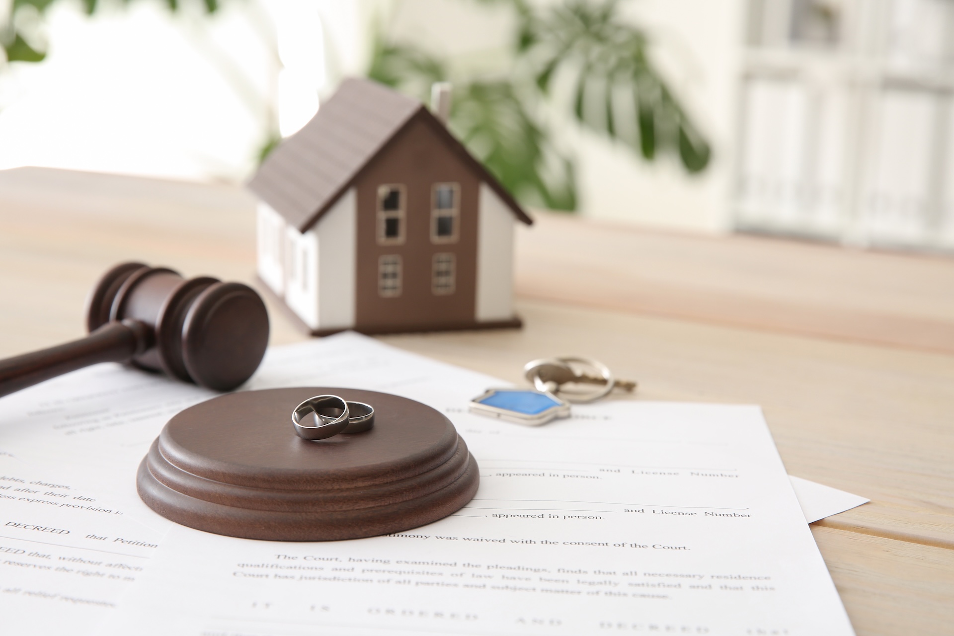 A gavel, two rings, and a small model house rest atop legal documents on a wooden table, symbolizing the Texas No-Fault Divorce Process: Step-by-Step Guide for 2025 and its focus on marriage, divorce, and property division.