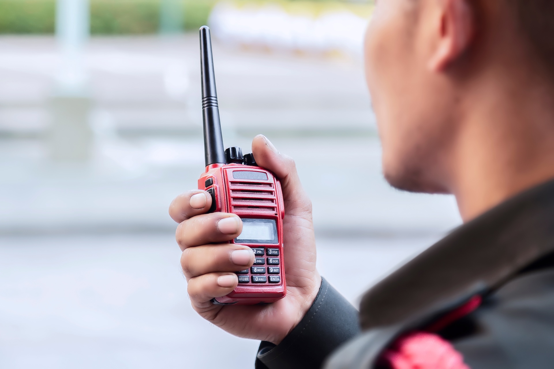 A uniformed officer holds a two-way radio while responding to a theft call A uniformed officer holds a two-way radio while responding to a theft call