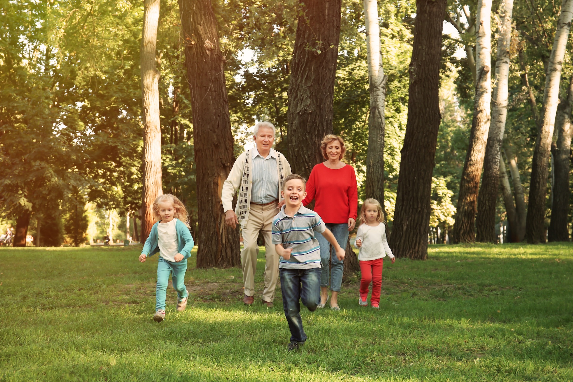Grandparents and grandchildren walking together along a path in a sunlit park. Grandparents and grandchildren walking together along a path in a sunlit park.