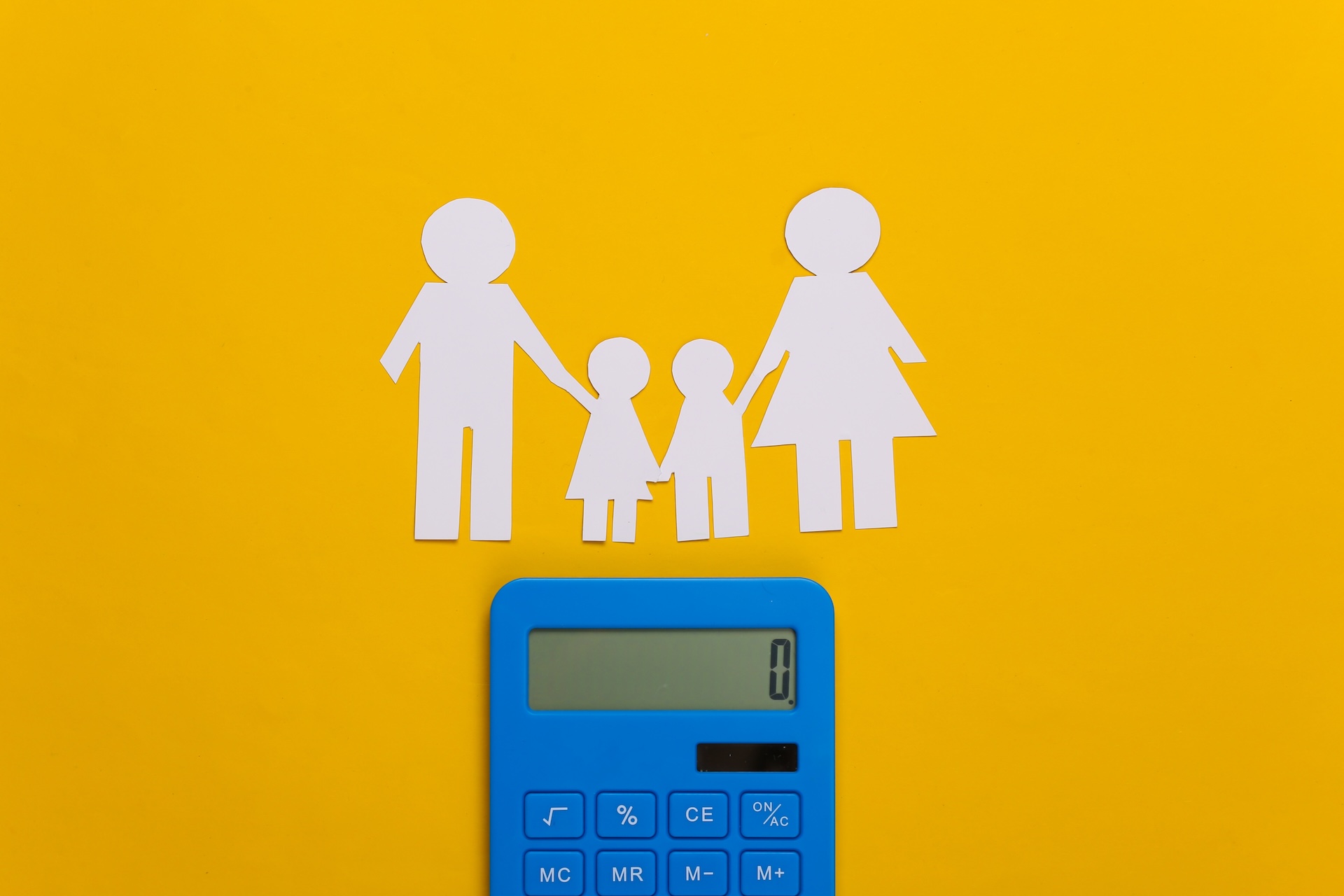 Paper cutouts of a family of four stand above a blue calculator displaying zero, all set against a bright yellow background.
