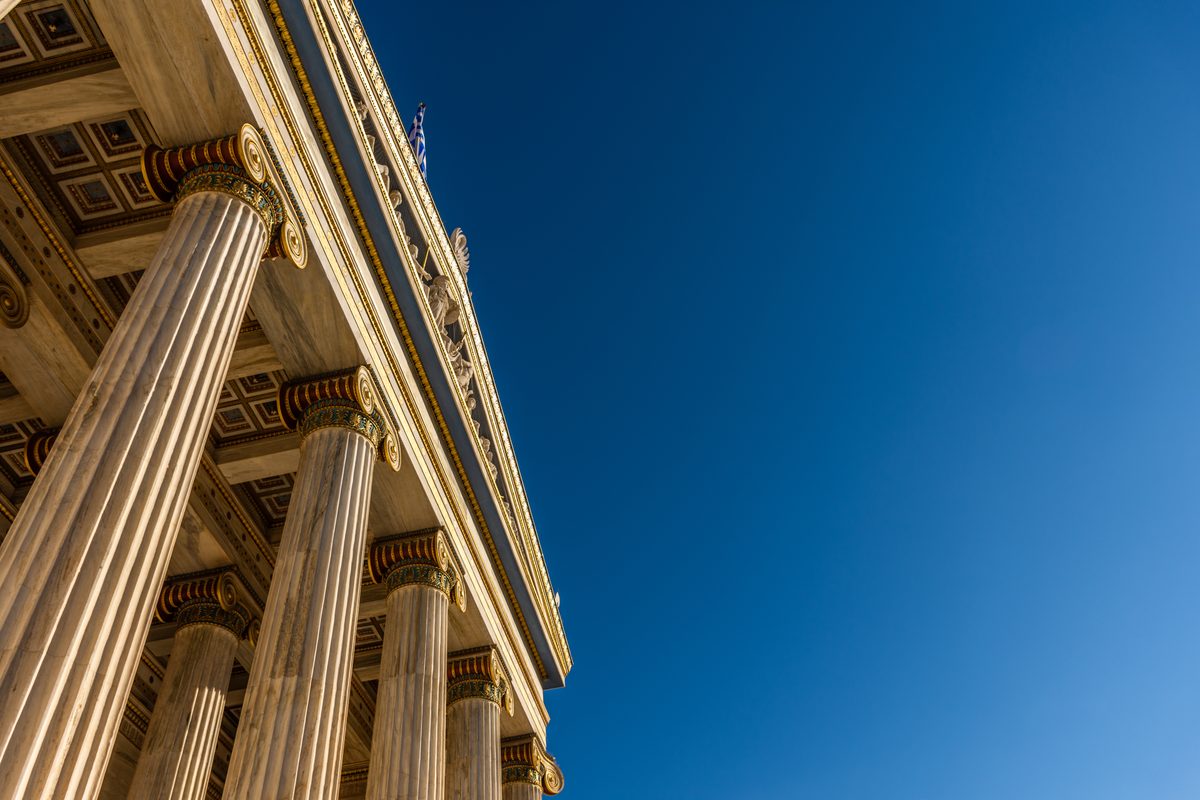 Tall classical marble columns on the facade of a courthouse building against a deep blue sky. Tall classical marble columns on the facade of a courthouse building against a deep blue sky.
