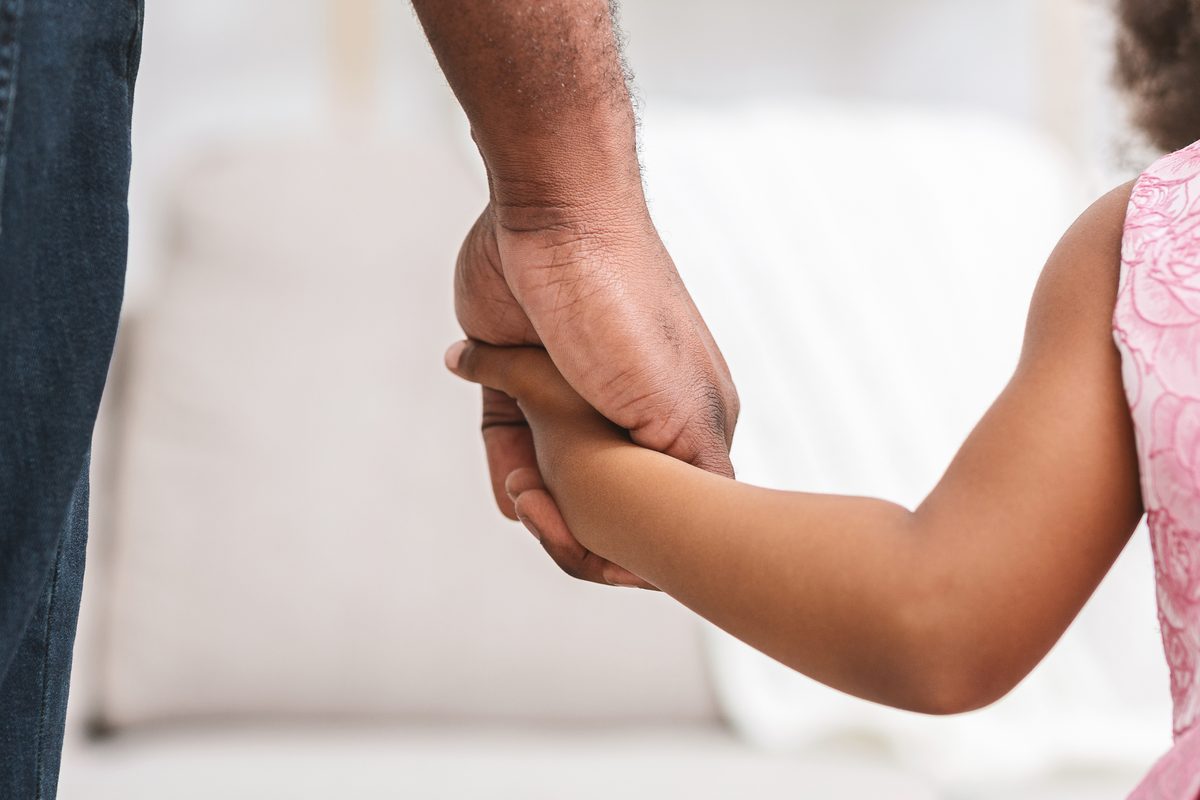 Close-up of a parent holding a young child's hand, representing the family consequences of a DWI with a child passenger.