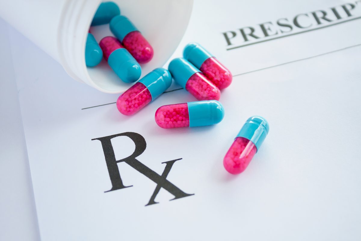 Prescription capsules spilling from a medication bottle onto a printed Rx prescription form. Prescription capsules spilling from a medication bottle onto a printed Rx prescription form.