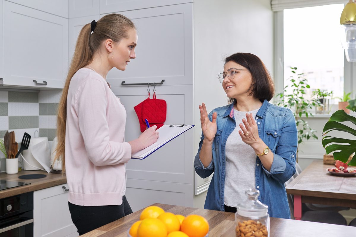Custody evaluator taking notes on a clipboard during a home visit with a parent