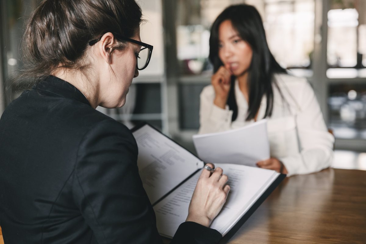 An interviewer reviews an applicant's paperwork during a job interview, where an old arrest can surface An interviewer reviews an applicant's paperwork during a job interview, where an old arrest can surface